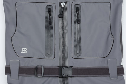 Close-up detail of BRIVER wader chest showing 100% waterproof TIZIP main zipper, water-resistant YKK chest pockets, and elastic wading belt.